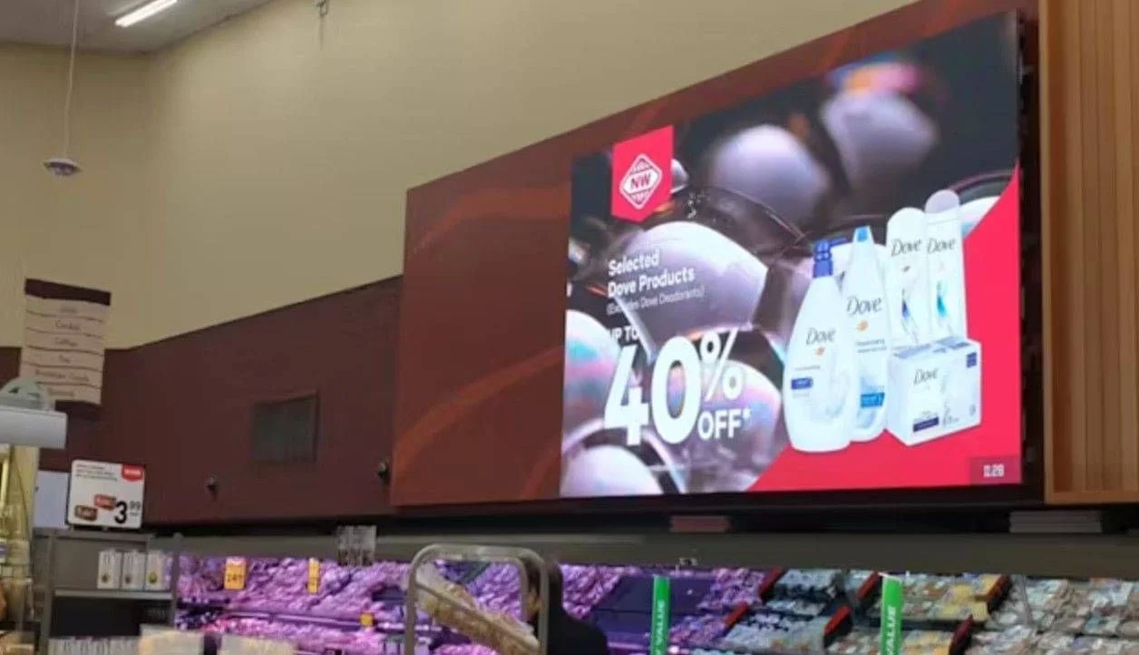 New World digital display showing a Dove promotion above retail shelves